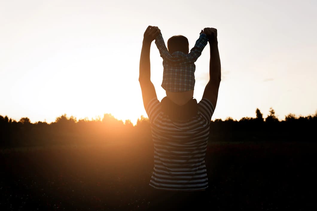 o pai e o filho que andam no campo no tempo do por do sol menino que senta se em equipa os ombros 8353 8198
