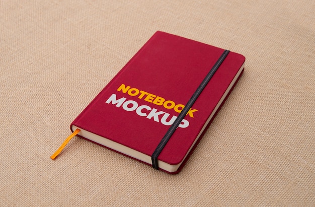 Notebook vermelho em maquete de superficie de tecid